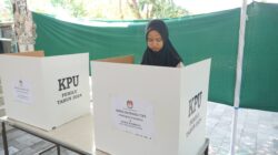 Seorang warga melakukan simulasi menggunakan hak pilihnya dengan mencoblos surat suara di bilik suara. (jogjakota.go.id)